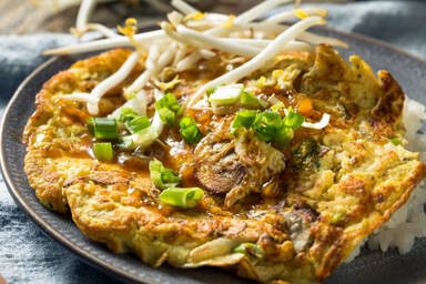 Egg Foo Young Omelet with bean sprouts and green onion circles and rice on a plate