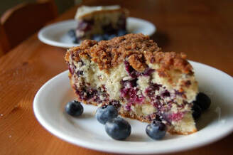 Slice of Fresh Blueberry Buckle on a plate with a plate in the background