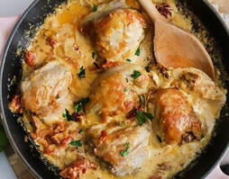 Pan of chicken thighs in creamy sauce with bacon
