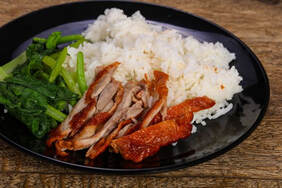 Sliced Duck, Broccolini, Rice on a black plate