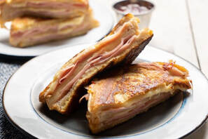 3 halves Monte Cristo Sandwich on two plates with jam in the backgroundPicture