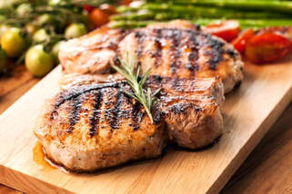 Grilled Pork Chops on Cutting Board surrounded by vegetables